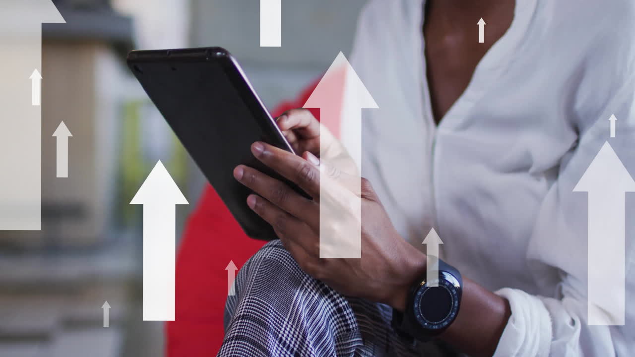 animación de flechas sobre mujer de negocios afroamericana usando tableta en la oficina