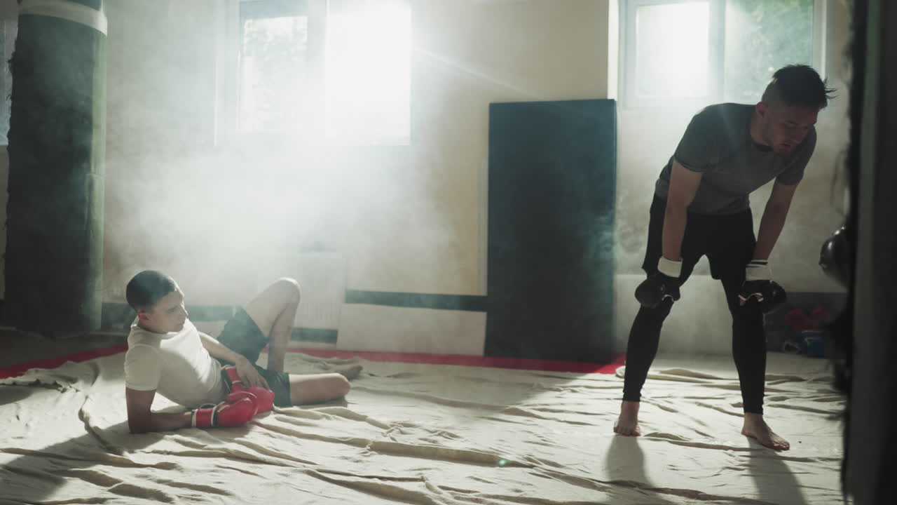 피곤한 남자들이 격렬한 운동을 한 후 휴식을 취하고 있습니다. 체력 운동으로 인한 피로감. 격렬한 체육 운동 후 피로감과 잉여 에너지.