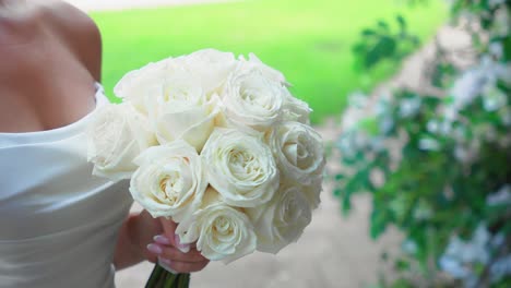 closeup shot of the white bridal bouquet with white roses in the hands of a beautiful bride outdoor on a wedding day