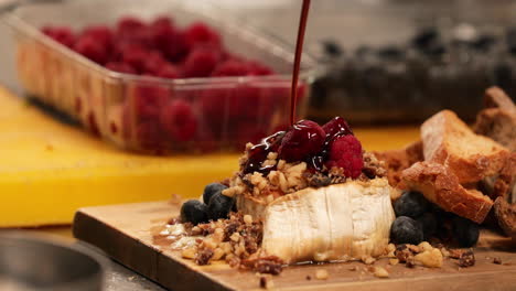 dripping raspberry sauce over bread with mixed berries and nuts