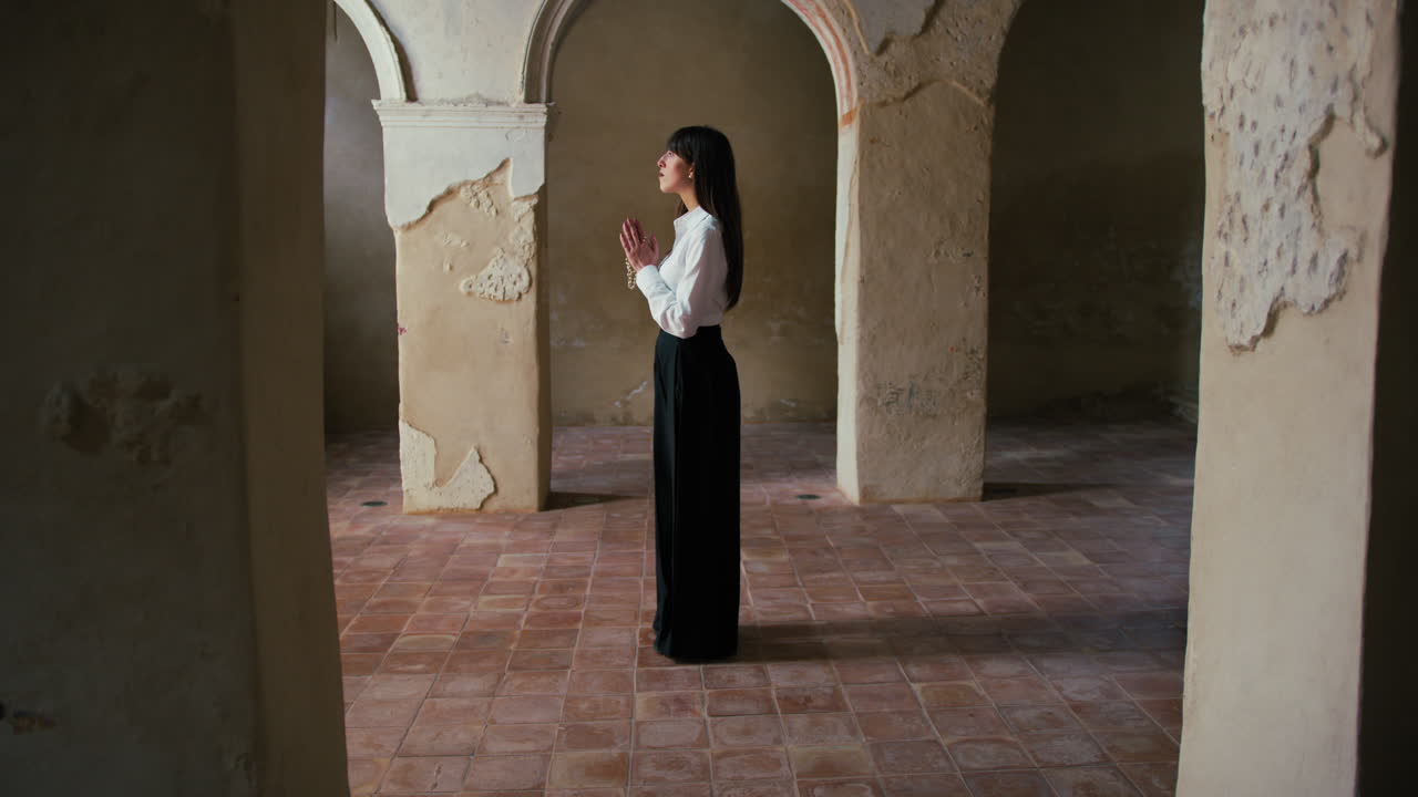 Woman Standing Still In The Middle Of An Old Church And Praying
