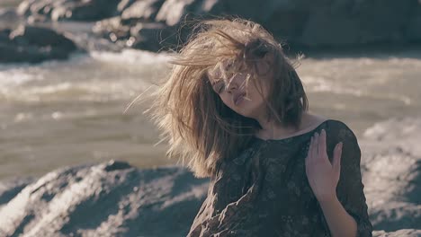 sensual girl poses at riverbank on windy day slow motion