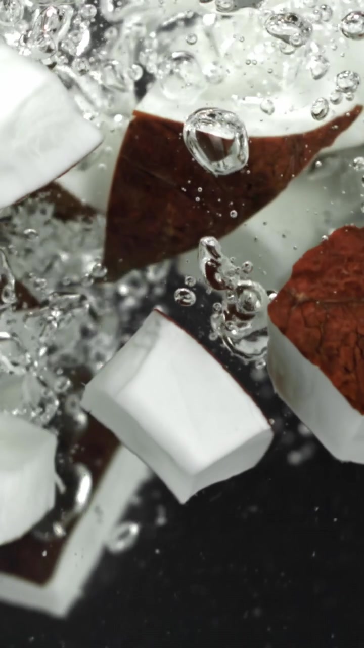 Pezzi di cocco che cadono nell'acqua limpida al rallentatore
