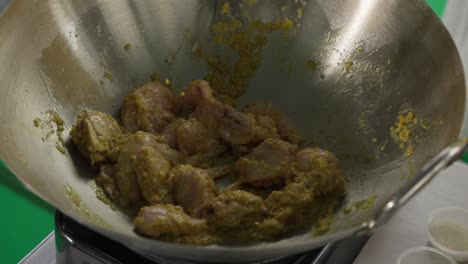 chicken cooking in turmeric marinade on hot wok, close-up shot of sizzling meat
