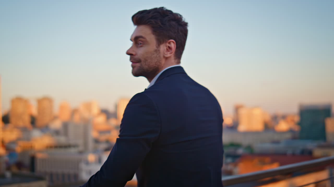 Elegant executive standing balcony overlooking cityscape in golden light closeup