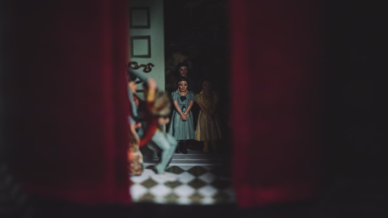 una familia de grupos de pequeñas figuras de muñecas de porcelana de vidrio figuras dentro de una oscura de mal humor mano pintada antigua casa de cortina roja vintage en miniatura de sombra