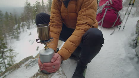 man using gas stove while camping on winter day