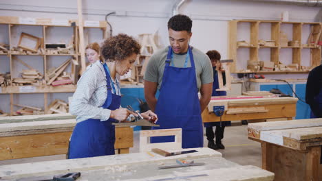 Nachhilfelehrer-Mit-Tischlerstudent-In-Der-Werkstatt,-Der-Für-Eine-Ausbildung-An-Der-Hochschule-Mit-Holzhobel-Studiert