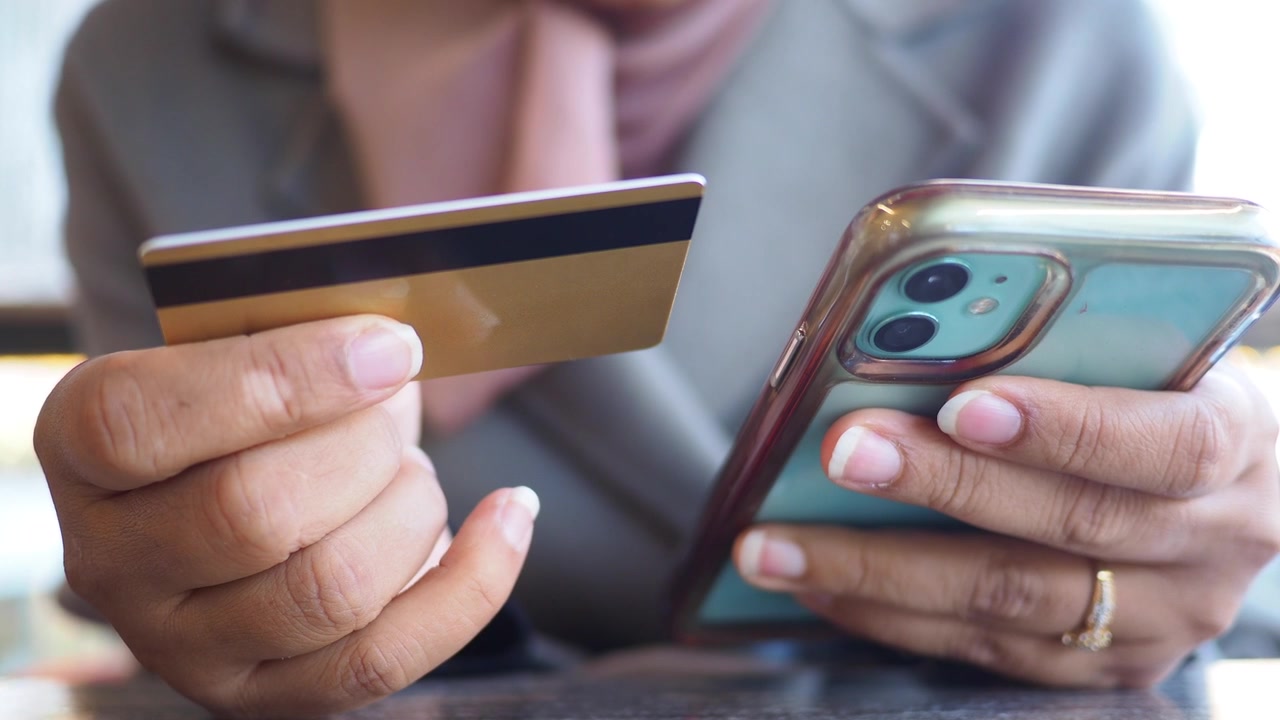 Persona che tiene in mano carta di credito e smartphone per pagamento online