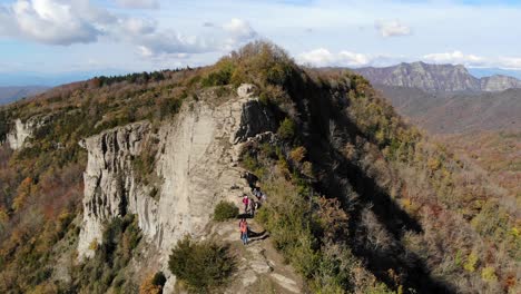 aerial: several hikers walking along a very narrow mountain crest in autumn season