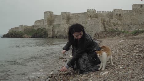 young and beautiful girl collecting stones on the seaside in front of a castle