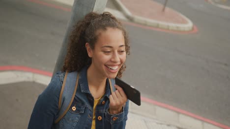 Mujer-Birracial-Feliz-En-La-Ciudad,-Hablando-Por-Teléfono-Inteligente-Y-Sonriendo