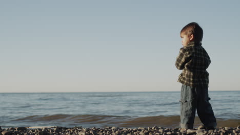 the kid stands on a rocky seashore