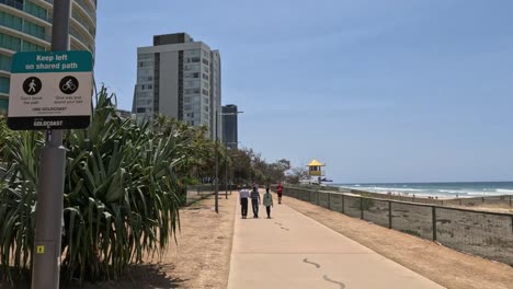 personas caminando a lo largo de un camino costero soleado con edificios