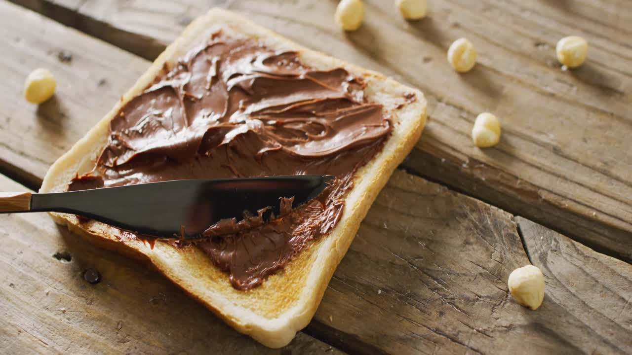 Vidéo en gros plan d'un toast à la pâte à tartiner au chocolat sur fond de bois