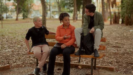 three young friends socializing on a park bench
