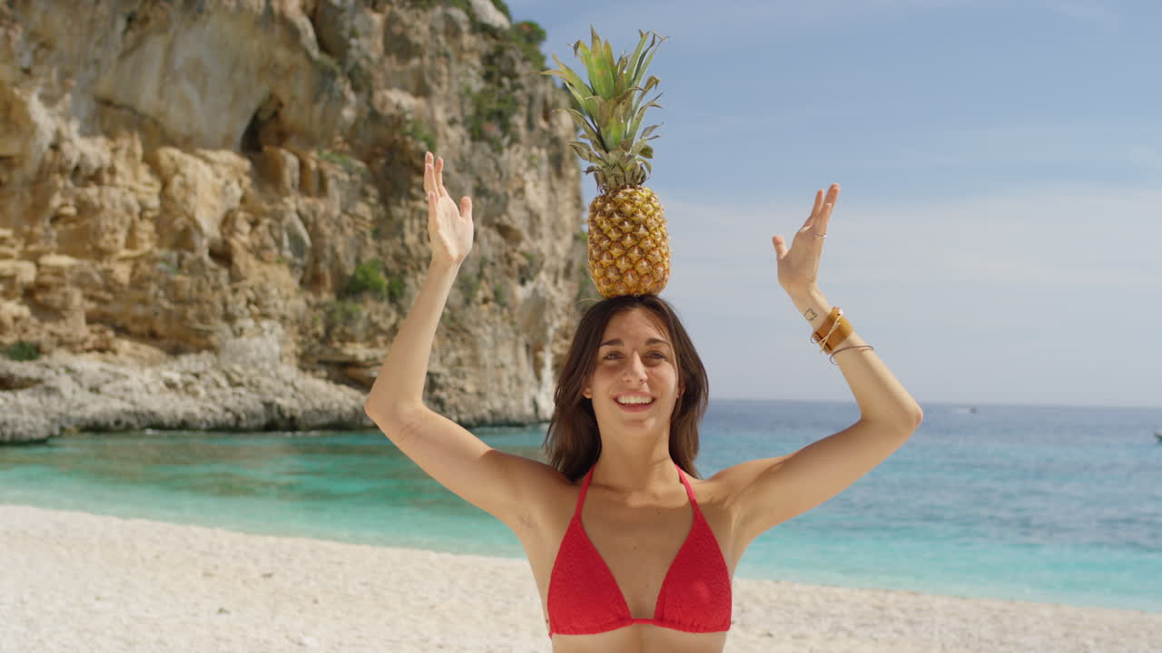 해변에서 머리에 파인애플을 가진 여자