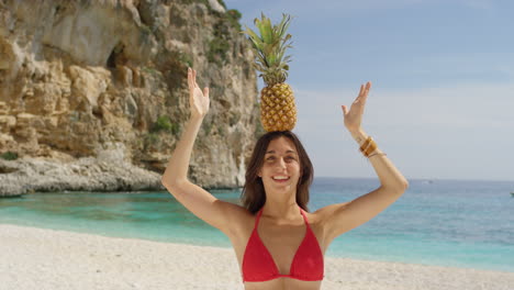 mujer con piña en la cabeza en la playa