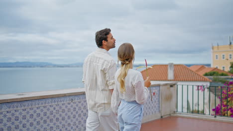 parejas encantadoras mirando paisaje marítimo arquitectura de la ciudad en romántico paseo hacia atrás vista