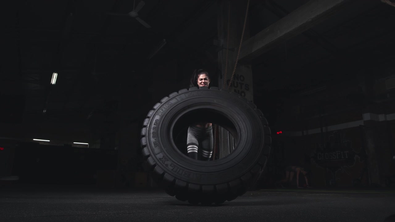 Young crossfit athlete doing a heavy tire flip in the gym