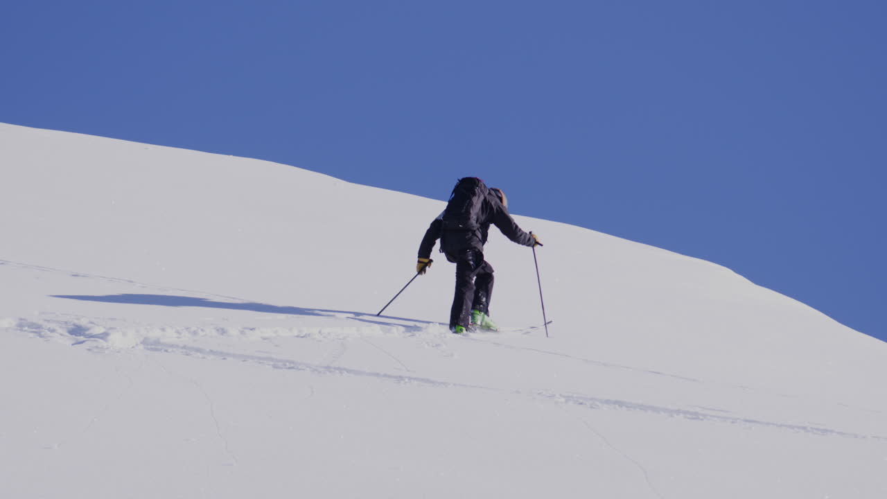 Freeride skier skinning up with Dents du Midi backdrop, then charging steep powder on a bluebird day near Champéry and Avoriaz.