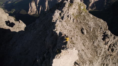 Mann-Auf-Unsicherem-Felsvorsprung-Mit-Blick-Auf-Malerisches-Tal,-Alpen