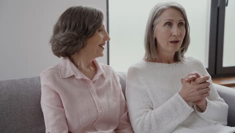 women happy senior friends sitting on the couch laughing and talking