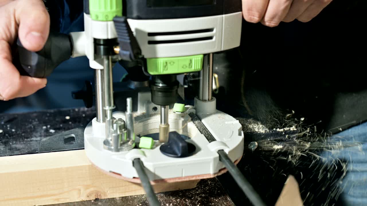 primer plano de la mano de un carpintero trabajando con un cortador eléctrico manual en un taller casero.