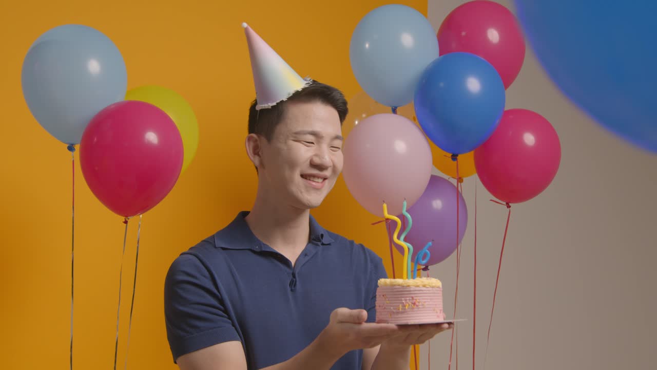 retrato de estudio de un hombre con un sombrero de fiesta celebrando su cumpleaños soplando velas en el pastel