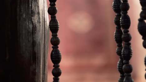 a close up shot of wooden beads curtain transition to a carpet on the wall, hotel restaurant in agra, india