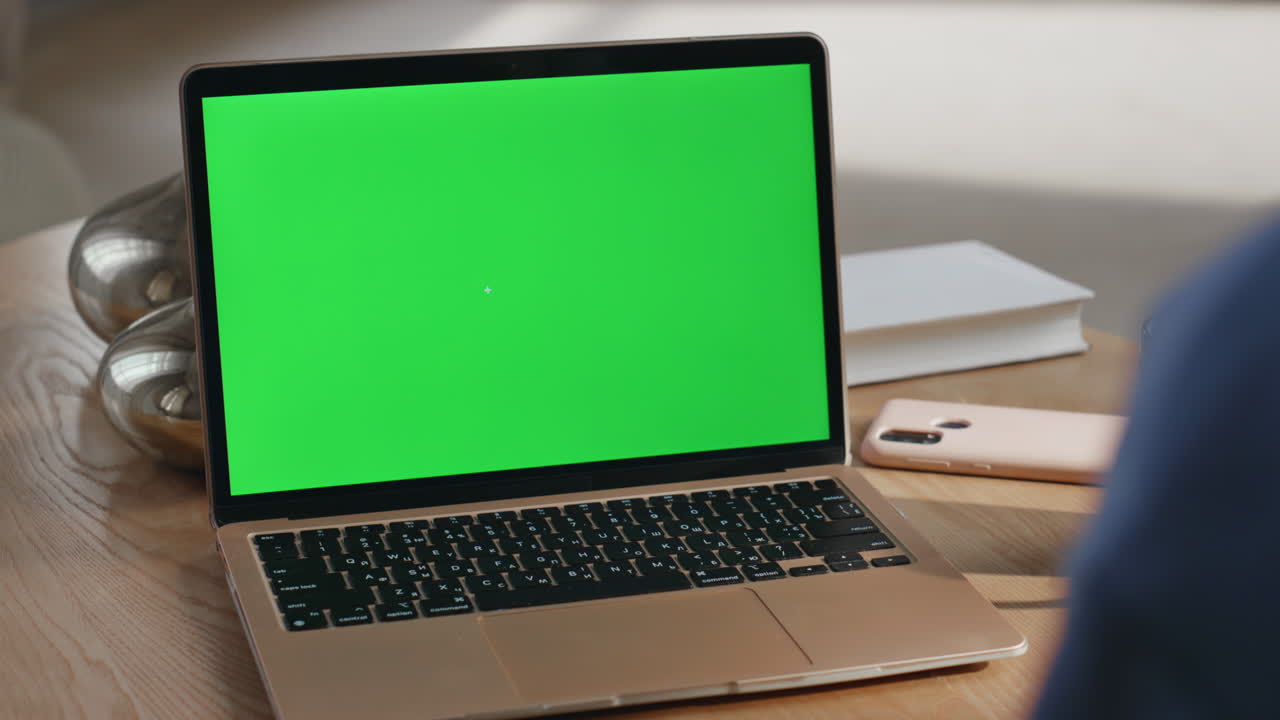 Laptop with green screen on a wooden table