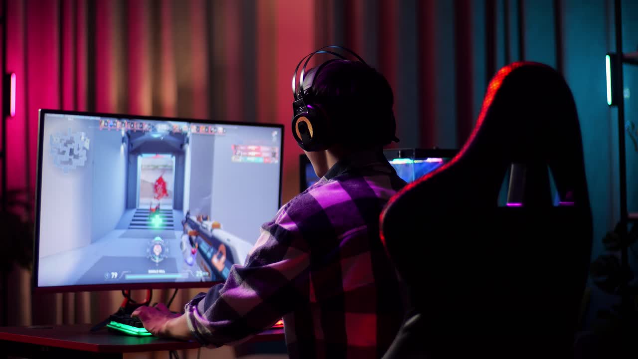 Ragazzo adolescente asiatico gamer entusiasta festeggia la vittoria mentre gioca a un videogioco al computer, un videogioco sparatutto online.