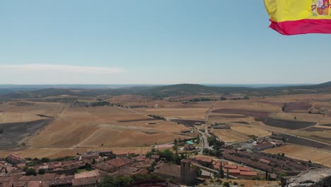 Drone-Despegando-Desde-Lo-Alto-De-Un-Castillo-Con-Vistas-A-Un-Pequeño-Pueblo-Y-Campos-Agrícolas