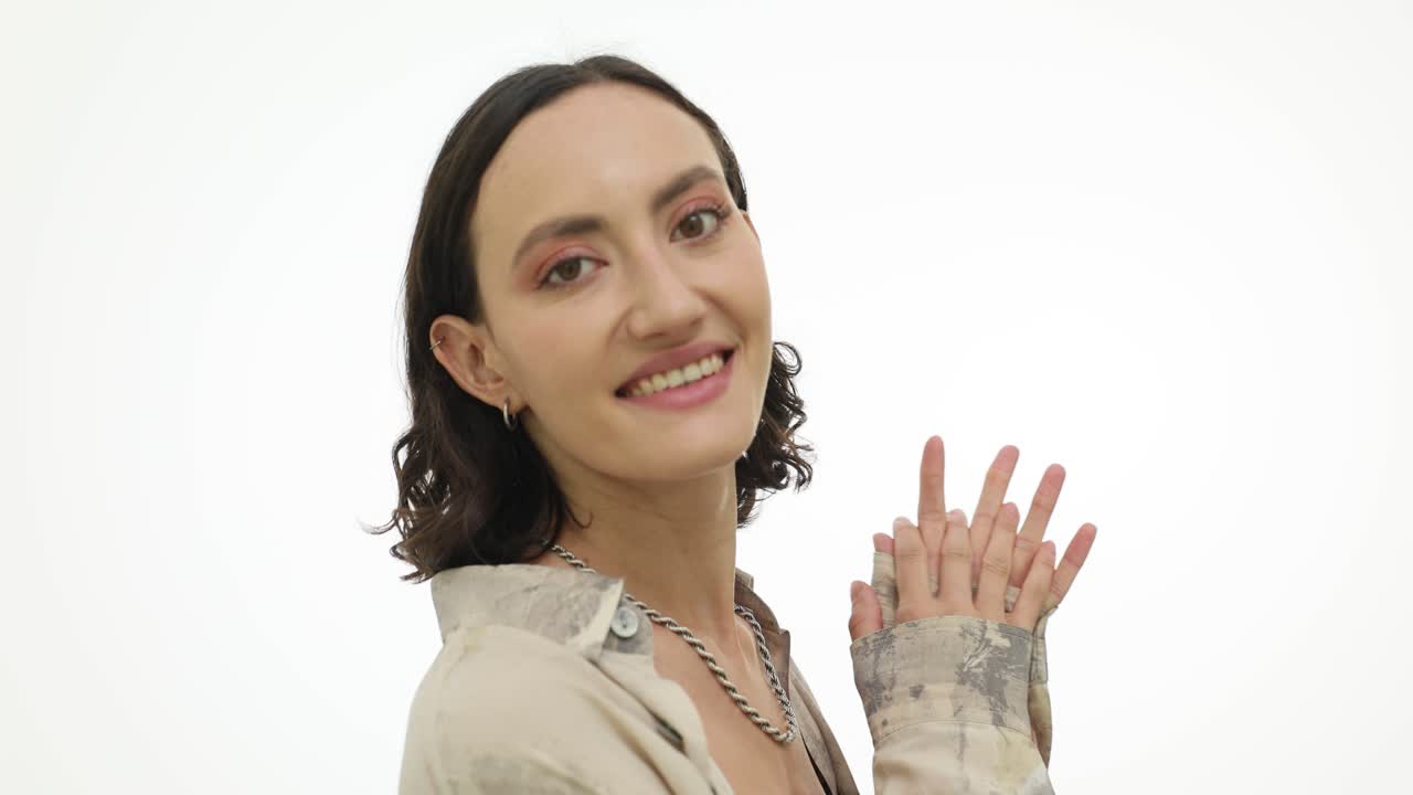 Smiling woman clapping and gesturing hands on a white background