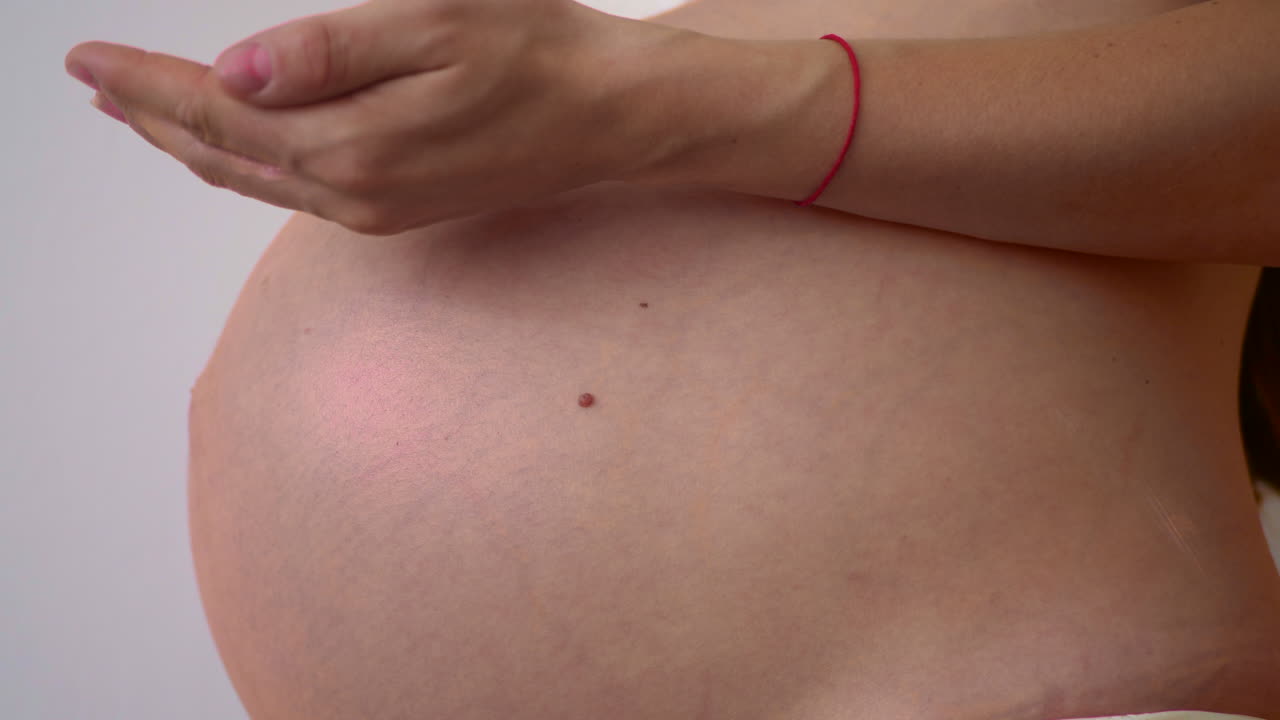 Donna incinta che applica una crema sulla pancia
