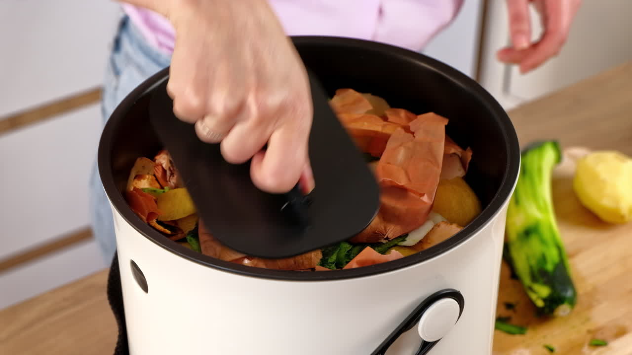 Woman recycling organic waste by composting vegetables peels in the Bokashi in the kitchen