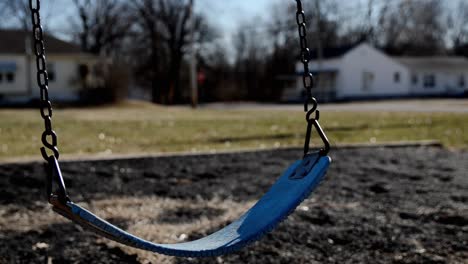 empty swings swaying in a school playground