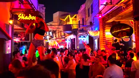 hot girl table dancing at a famous popular party street in bodrum turkey holiday, fun summer nights on vacation, 4k shot