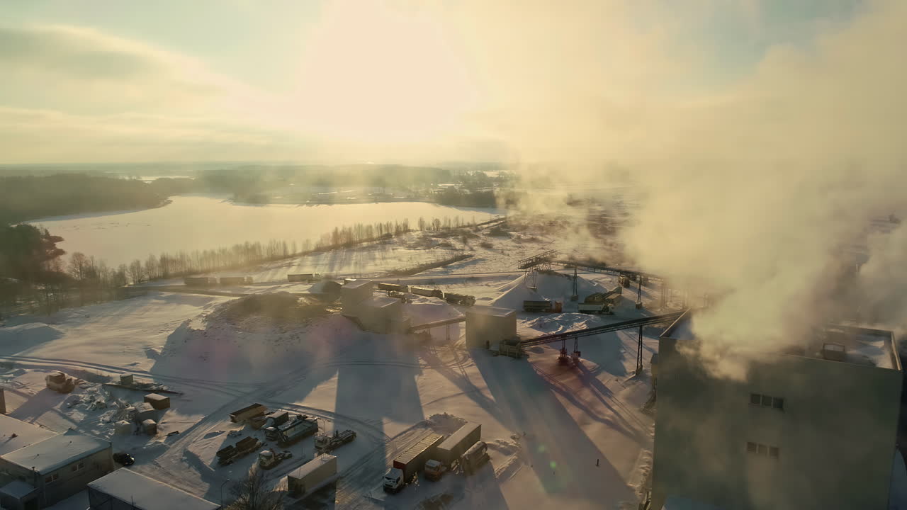 Ripresa con drone di una fabbrica di cellulosa che emette vapore, con il terreno coperto di neve.