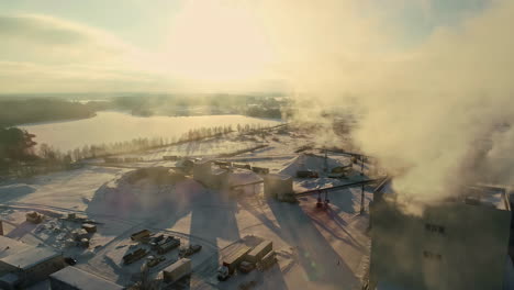 drone shot of a pulp mill pumping out steam with snow covering the ground