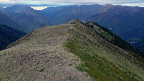 drone shot top down on the gras of a field and then panning to the mountain range