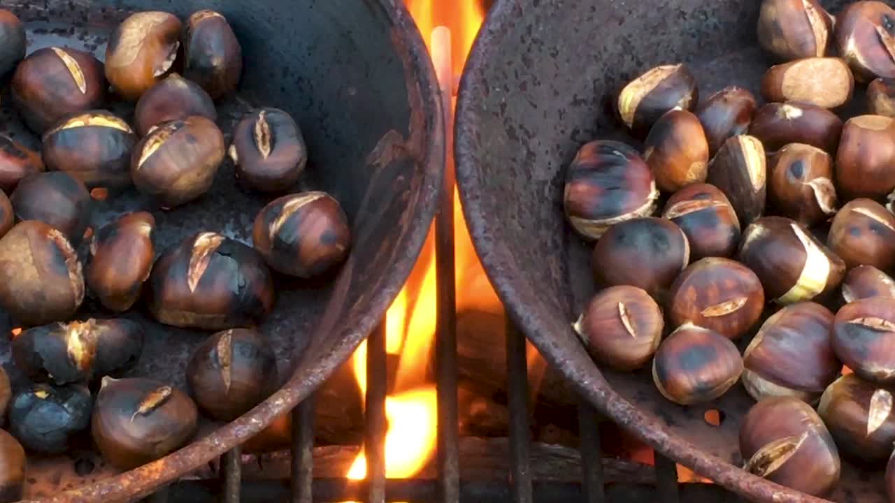 castañas asadas en fuego abierto, manjar de temporada, cosecha, 1920 hd, comida favorita de las vacaciones, de cerca, asado en sartén de hierro, dolly deslizante tiro de derecha a izquierda
