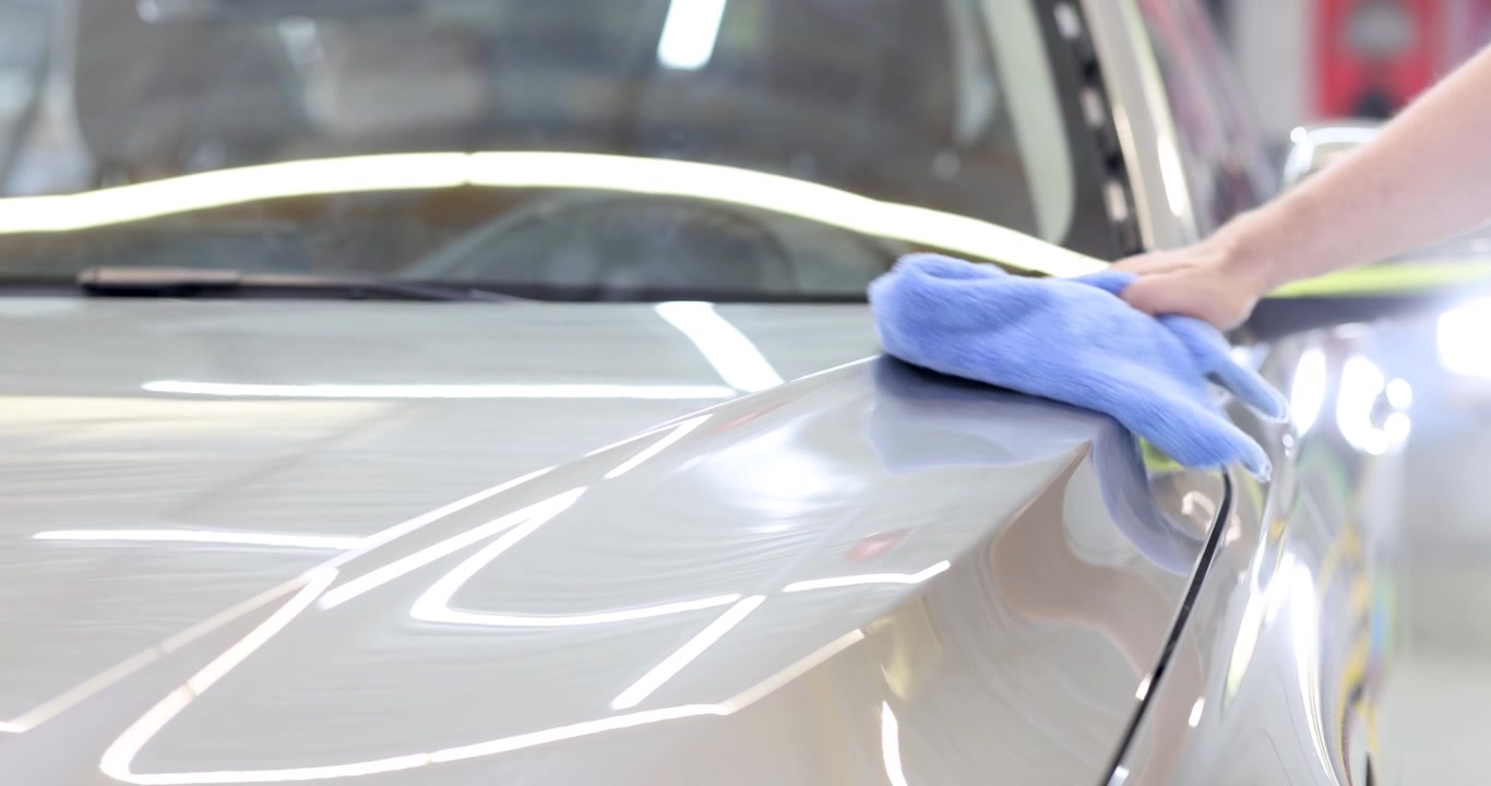 Person wipes down hood of car with soft blue microfiber cloth
