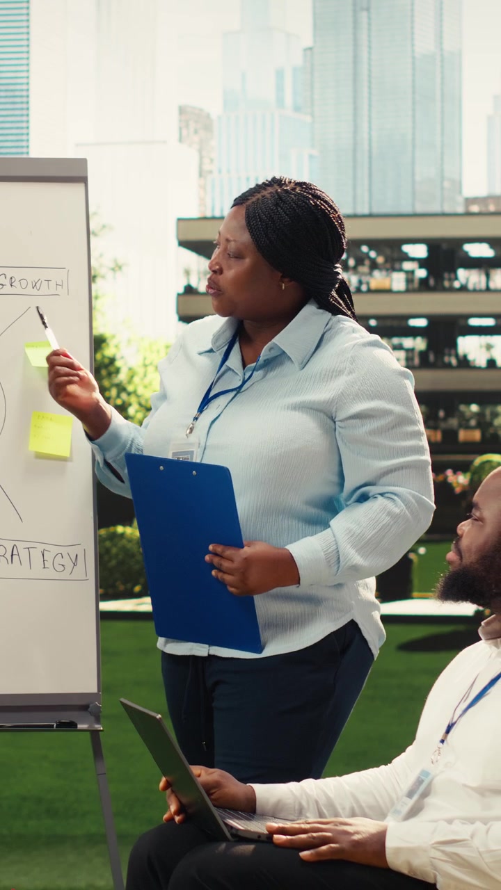 Vertical Video Diverse coworkers leading action plan discussion with whiteboard