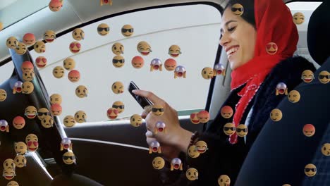 animación de emojis que caen sobre una mujer con hijab usando un teléfono inteligente