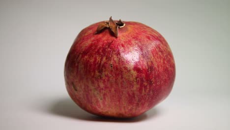 Iluminación-En-Movimiento-Sobre-La-Fruta-De-La-Granada-Sobre-Un-Fondo-Blanco