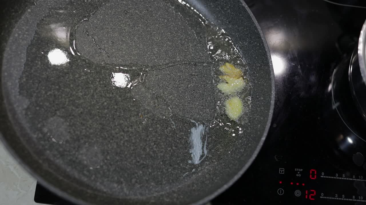 Fried sliced garlic and boiling food oil in the black pan
