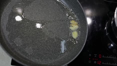 fried sliced garlic and boiling food oil in the black pan