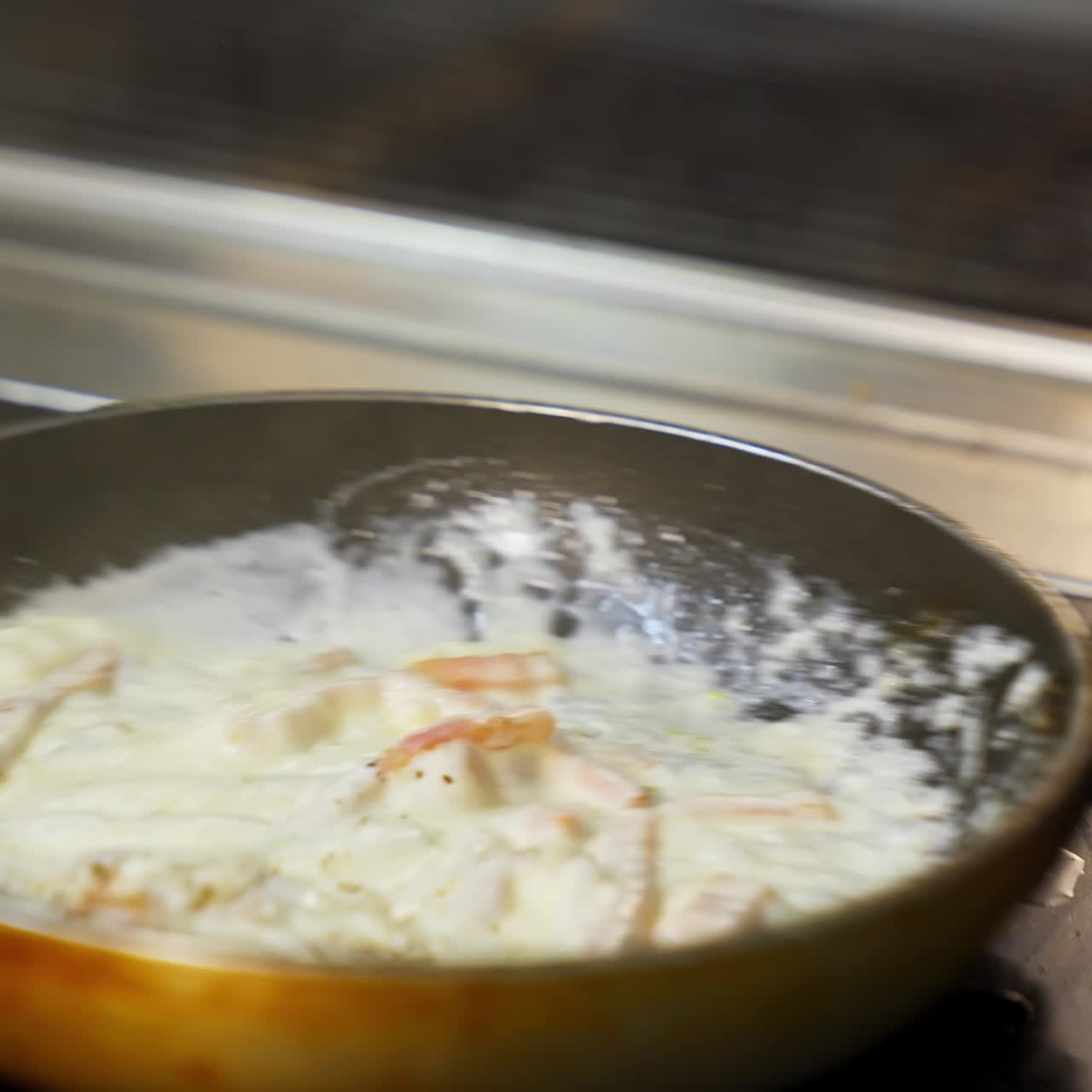 Cooking delicious meal in white sauce. Chef is cooking tasty dish in a frying pan in a restaurant. Close-up