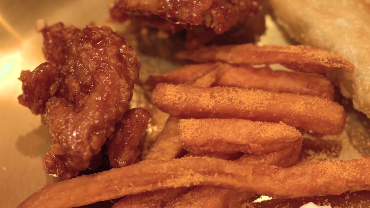 Toma macro de pollo frito glaseado, patatas fritas sazonadas y empanadillas en un plato de latón